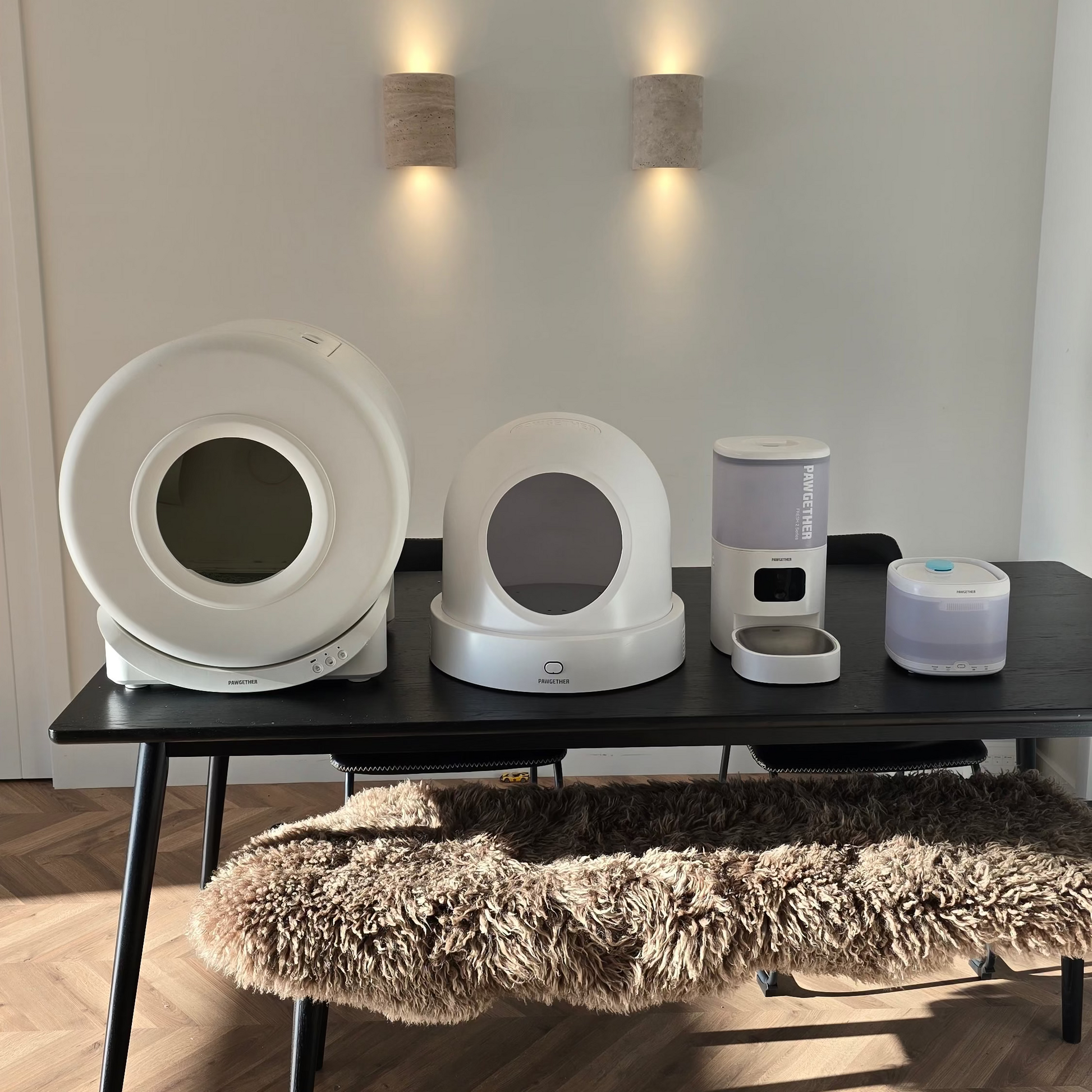 Set of white electronic devices on a black table with a textured rug in the foreground.